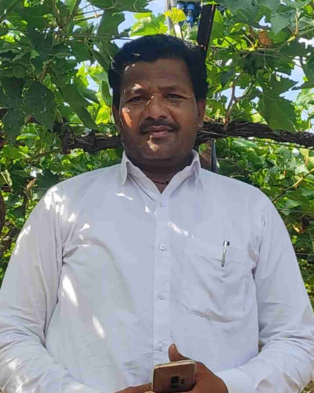 A happy chilli cultivator holding a basket of fresh red chillies on his farm in Guntur.